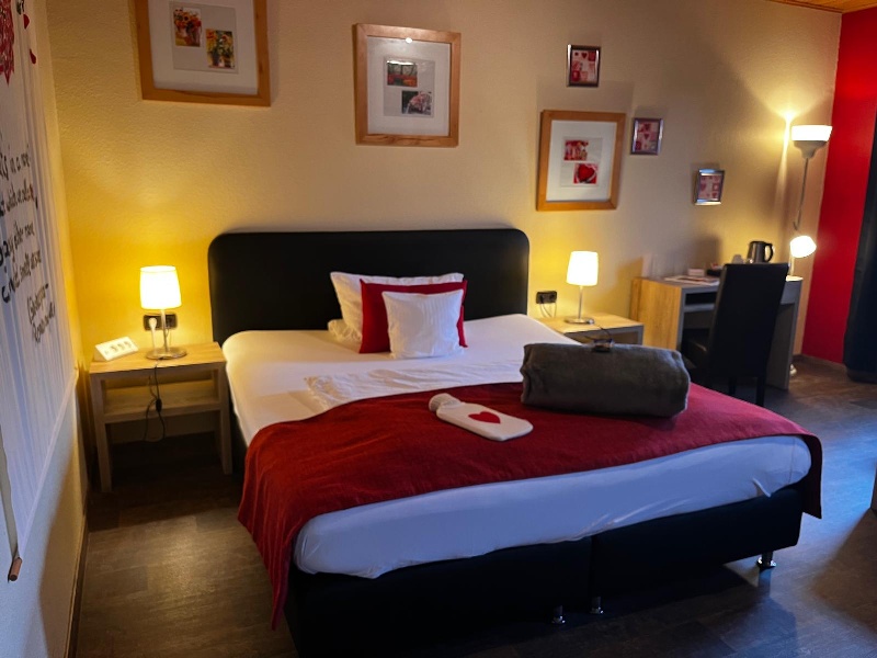 Gemütliches Hotelzimmer mit einem Doppelbett, Nachttischen und Schreibtisch.